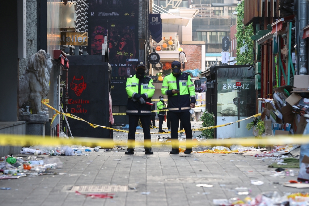 Policemen stand guard at the scene where a stampede during Halloween festivities killed and injured many people at the popular Itaewon district in Seoul, South Korea, October 30, 2022. Yonhap via REUTERS