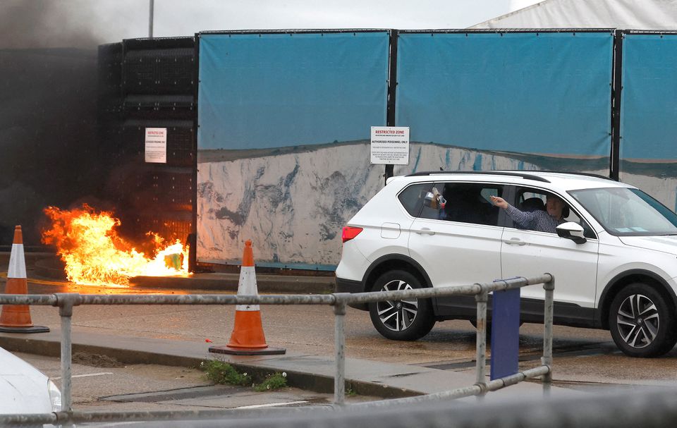 A man throws an object out of a car window next to the Border Force centre after a firebomb attack in Dover, Britain, October 30, 2022. Reuters/Peter Nicholls
