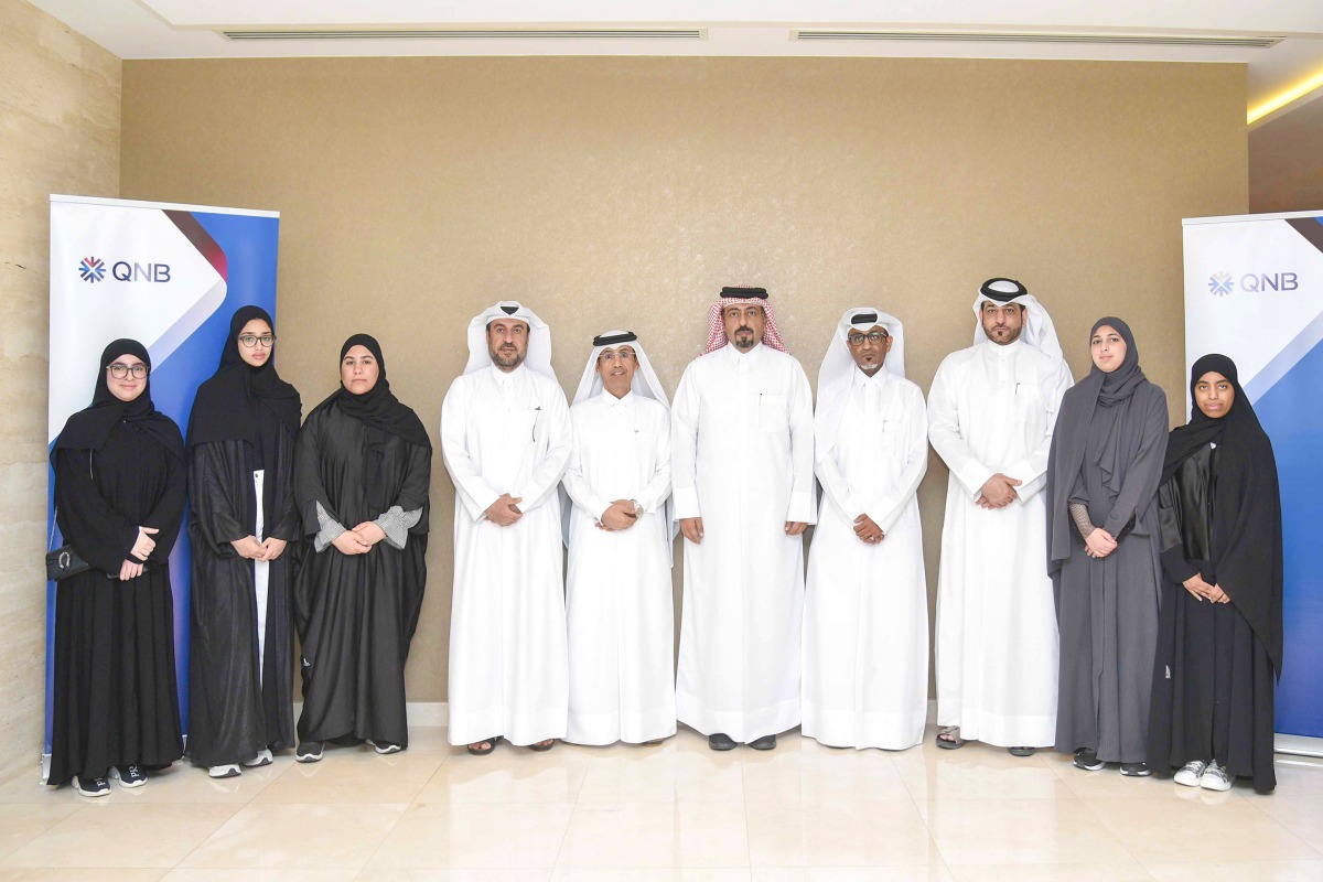 QNB officials and Qatar Banking Studies and Business Administration Secondary School students pose for a group photo.