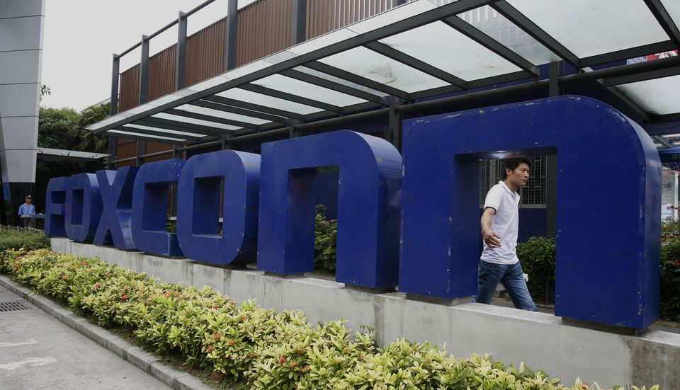 A man walks past a company logo at the entrance to a Foxconn factory in the township of Longhua in the southern Guangdong province May 27, 2010. File Photo / Reuters
