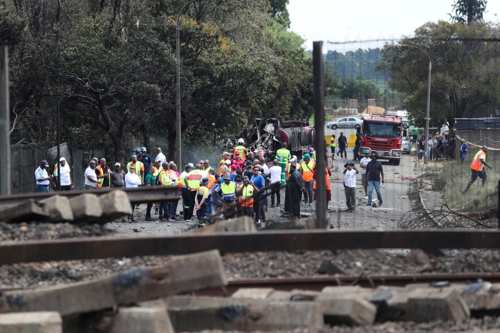 People gather near a burnt out truck at the entrance of the damaged bridge where a gas tanker exploded in Boksburg near Johannesburg, South Africa, on  December 24, 2022. REUTERS/Sumaya Hisham