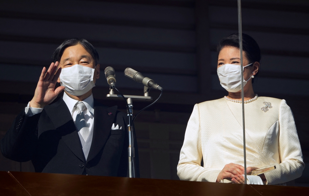 Japan's Emperor Naruhito (L) and Empress Masako (R) wave to well-wishers through a bullet-proof glass from a balcony during their New Year's public appearance at the Imperial Palace in central Tokyo, Japan, 02 January 2023. FRANCK ROBICHON/Pool via REUTERS