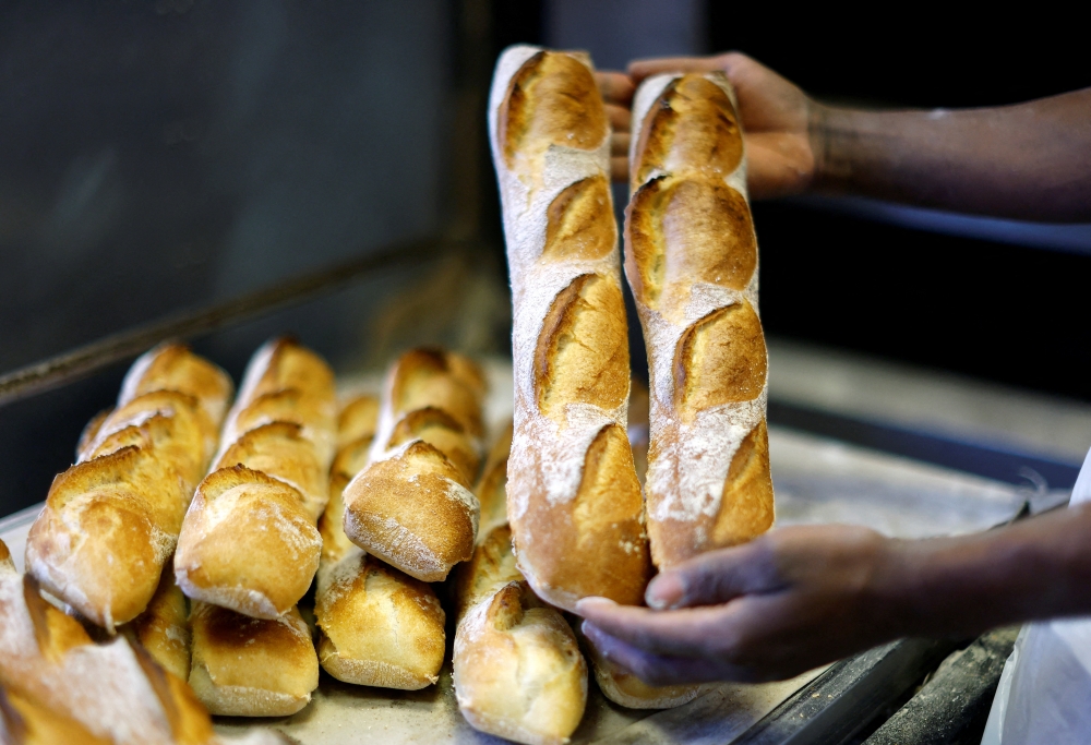 A baker shows freshly-bakedÊbaguettes at 