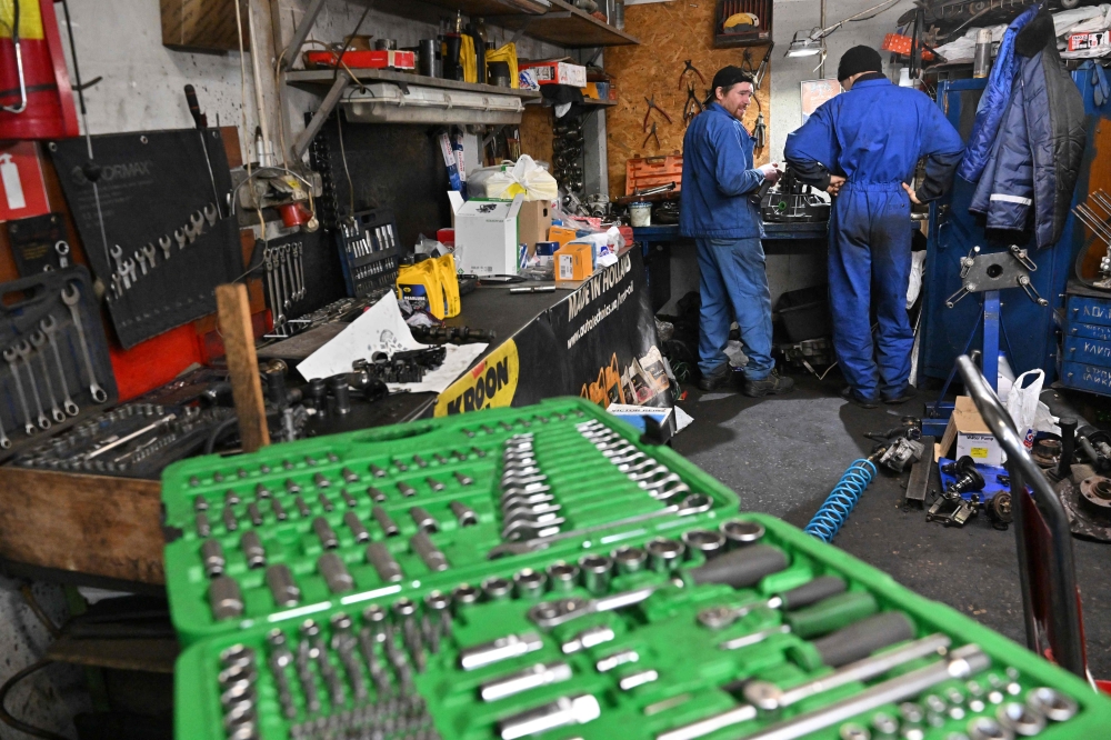 Mechanics work in a auto repairing shop in Ukrainian capital of Kyiv on December 30, 2022. Photo by Sergei SUPINSKY / AFP