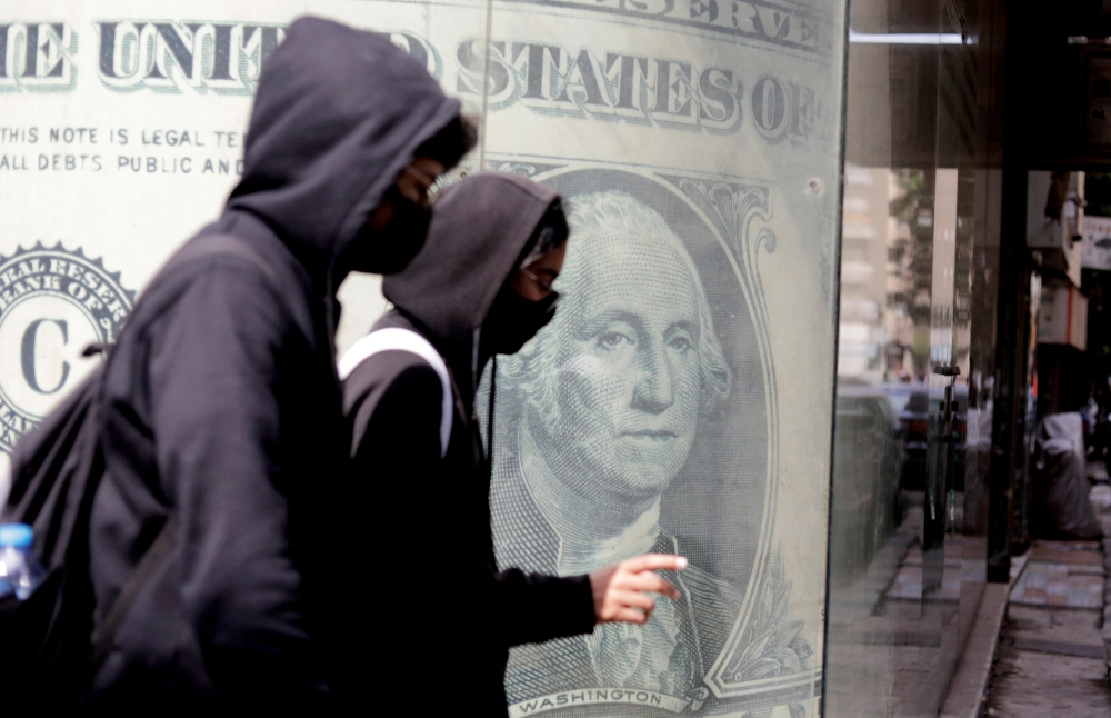 People walk past a currency exchange point, showing an image of the US dollar in Cairo, Egypt, on March 22, 2022. File Photo / Reuters