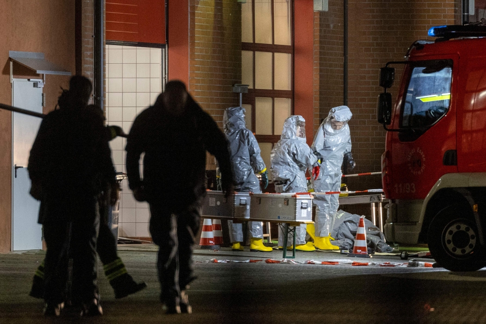 Agents wearing protective suits examine substances on the premises of the fire brigade in Castrop-Rauxel, western Germany on January 8, 2023 following arrests on suspicion of preparing an attack using cyanide and ricin. (Photo by Christoph Reichwein / DPA / AFP)

