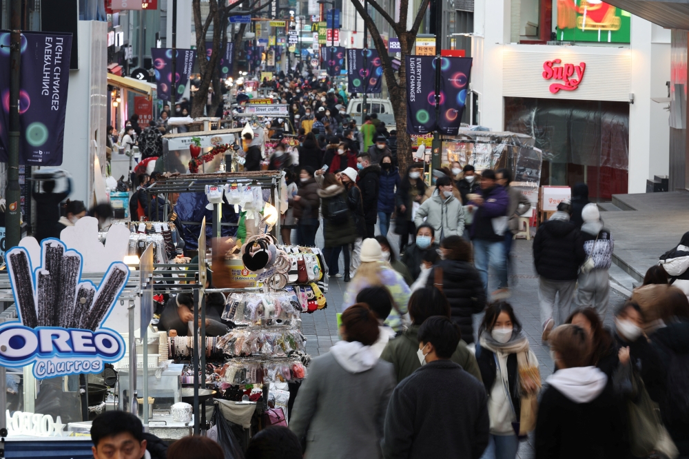 Street vendors (L) wait for customers at Myeongdong shopping district in Seoul, South Korea, January 9, 2023. REUTERS/Kim Hong-Ji

