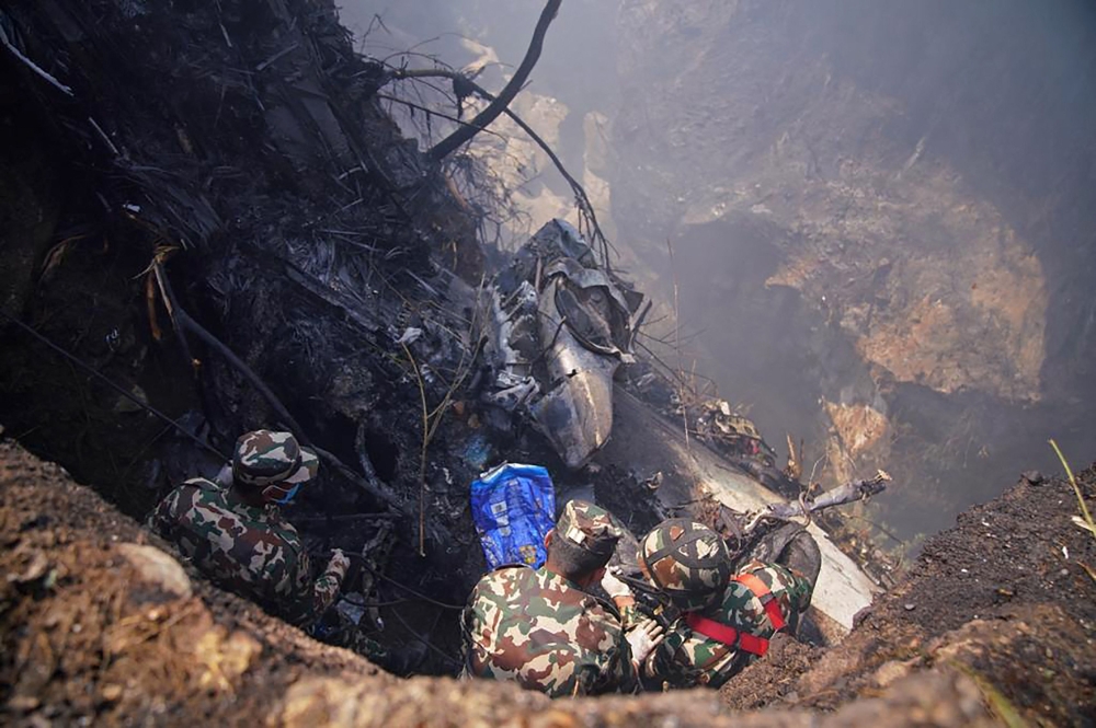Rescuers inspect the site of a plane crash in Pokhara on January 15, 2023. An aircraft with 72 people on board crashed in Nepal on January 15, Yeti Airlines and a local official said. (Photo by Yunish Gurung / AFP)