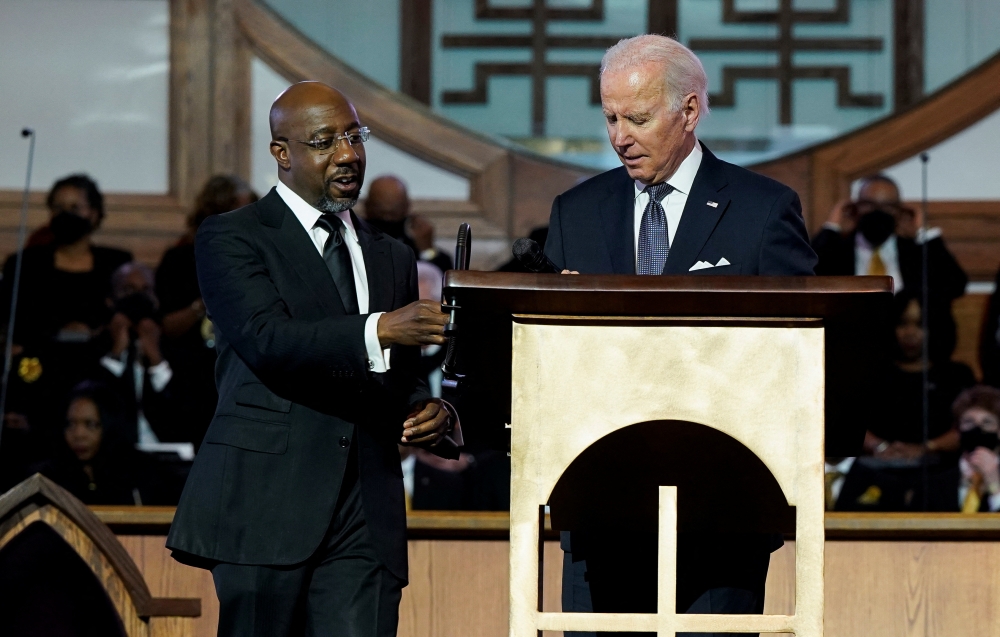 US President Joe Biden stands next to Senator Raphael Warnock (D-GA), a senior pastor at Ebenezer Baptist Church, ahead of the holiday honoring Martin Luther King Jr., in Atlanta, Georgia, US, on January 15, 2023. REUTERS/Joshua Roberts