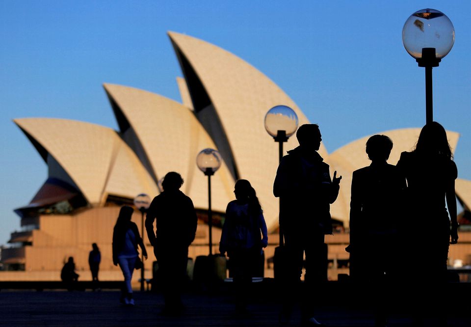 People are silhouetted against the Sydney Opera House at sunset in Australia, November 2, 2016. File Photo: REUTERS/Steven Saphore
