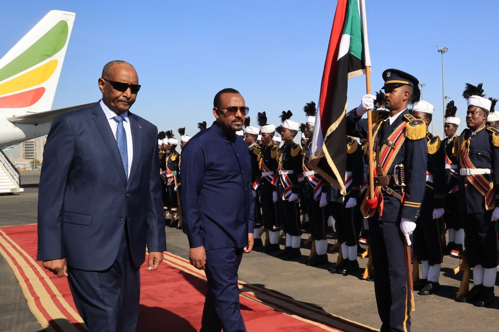 Ethiopian Prime Minister Abiy Ahmed (R) walks alongside Sudanese Army Chief Abdel Fattah al-Burhan (L) at Khartoum Airport during a welcome ceremony on January 26, 2023. (Photo by AFP)