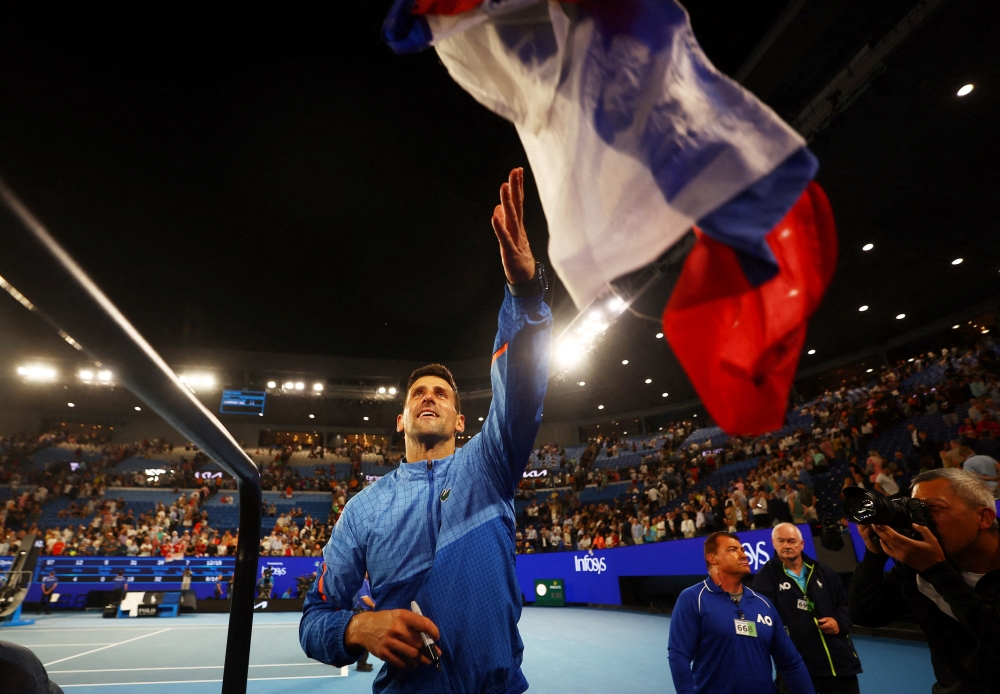 Serbia’s Novak Djokovic signs autographs for fans after winning his semi final match against Tommy Paul of the US at the Australian Open in Melbourne on January 27, 2023. (REUTERS/Hannah Mckay)