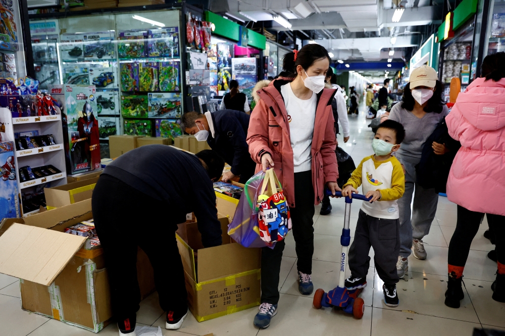 A woman and a child walk past workers sorting toys at a shopping mall in Beijing, China on January 11, 2023. File Photo / Reuters