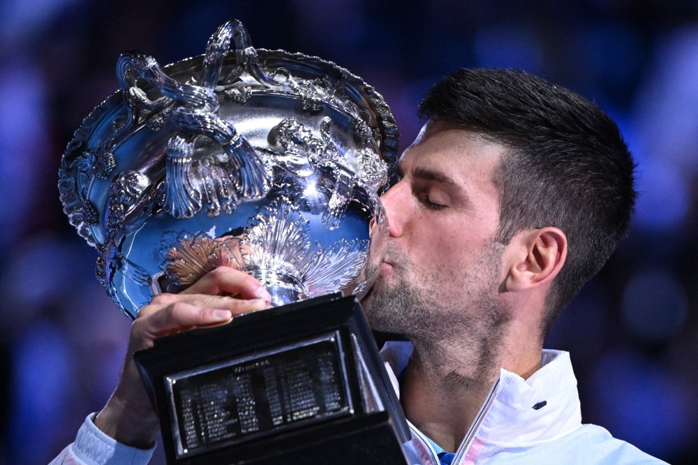Serbia's Novak Djokovic poses with the Norman Brookes Challenge Cup after his victory against Greece's Stefanos Tsitsipas during the men's singles final of the Australian Open tennis tournament in Melbourne on January 29, 2023. (Photo by William West/AFP)