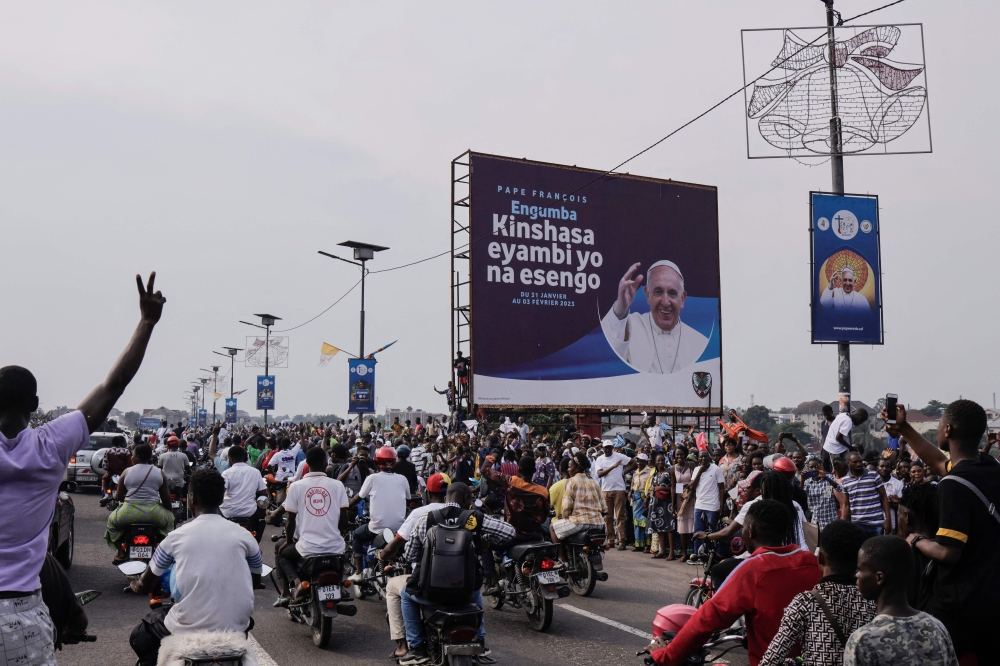 People gather on the side of the road to get a glimpse of Pope Francis (not seen) as he departs the N'djili International Airport in Kinshasa, Democratic Republic of Congo (DRC), on January 31, 2023. (Photo by Guerchom Ndebo / AFP)