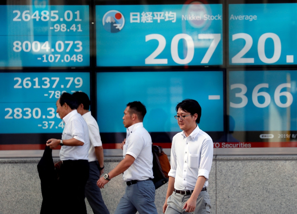 Men walk past in front of an electric screen showing Japan's Nikkei share average outside a brokerage in Tokyo, Japan, August 5, 2019. File Photo: REUTERS/Issei Kato