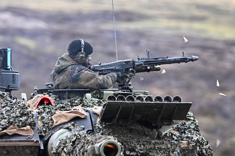 A tank crew member fires a tank mounted machine gun as German Defense minister Boris Pistorius visits Leopard II tanks that are due to be supplied to Ukraine at the tank brigade Lipperland of Germany's army and part of the Bundeswehr, in Augustdorf, Germany, February 1, 2023. (REUTERS/Benjamin Westhoff)
