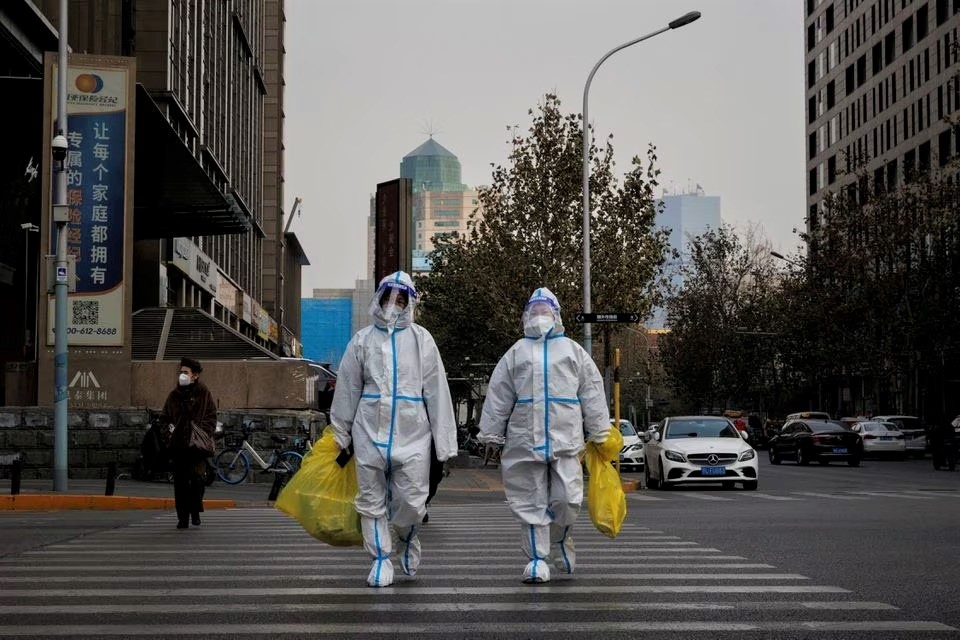 Pandemic prevention workers in protective suits cross a street as coronavirus disease (COVID-19) outbreaks continue in Beijing, December 9, 2022. (REUTERS/Thomas Peter)