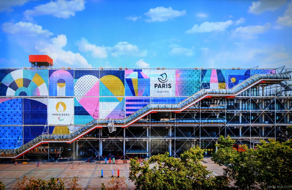 This photograph taken on February 8, 2023, shows an illustration of the dominant colours and visual identity on the Centre Pompidou, displayed on a screen during the presentation of the pictograms of each discipline and visual identity of Paris 2024 and Olympic and Paralympic Games, in Saint-Denis, north of Paris. (Photo by FRANCK FIFE / AFP)