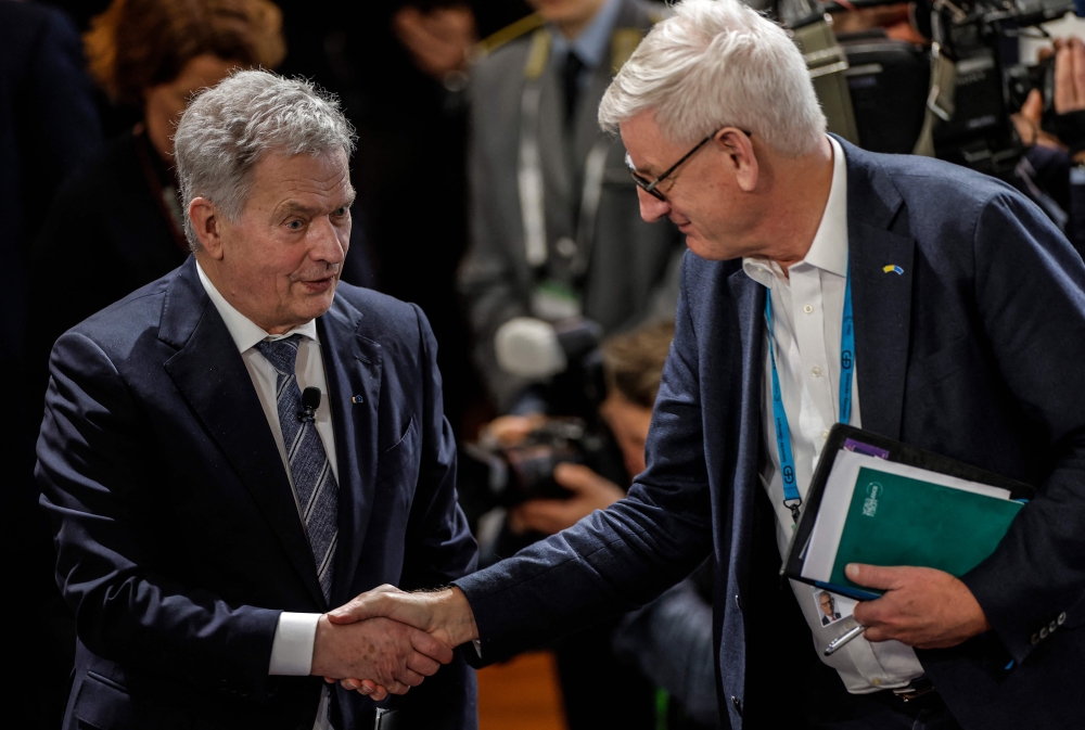 Finland's President Sauli Niinisto (left) shakes hands with Former Prime Minister of Sweden Carl Bildt at the Munich Security Conference (MSC) in Munich, southern Germany, on February 18, 2023.  (Photo by Odd ANDERSEN / AFP)