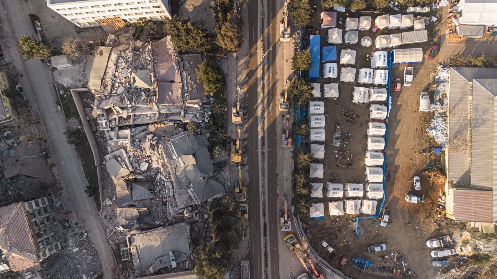 This aerial photograph taken on February 20, 2023 collapsed buildings next to a makeshift camp in Antakya, southern Turkey. (Photo by Sameer Al-DOUMY / AFP)