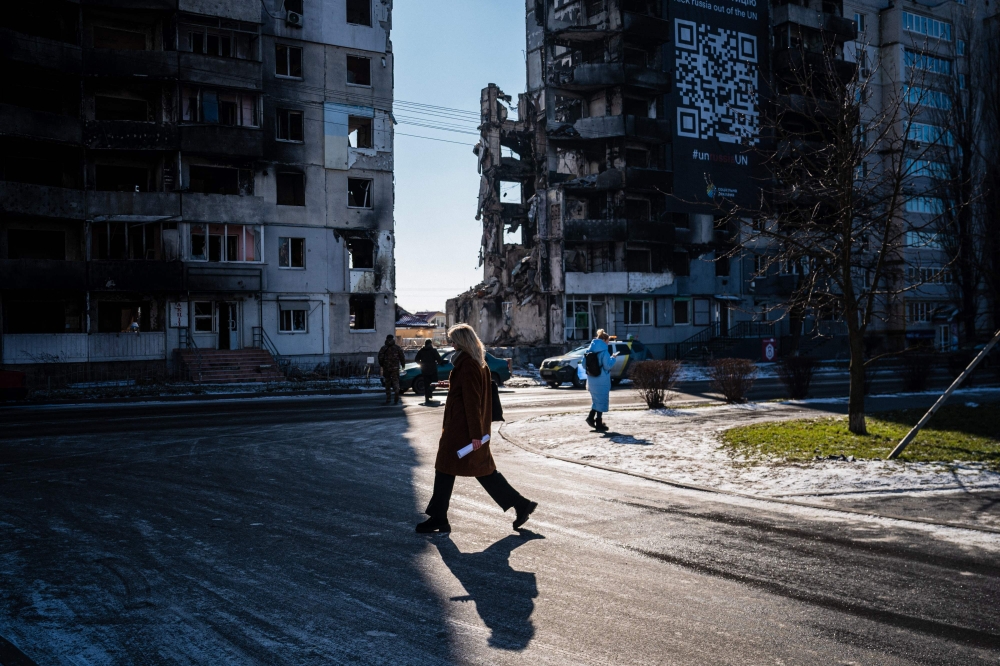 A woman walks next to a residential building, destroyed during an attack, in Borodyanka on February 23, 2023, amid Russia's military invasion on Ukraine. Photo by Dimitar DILKOFF / AFP 