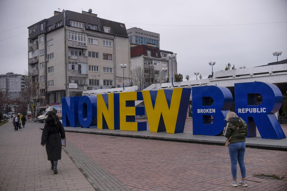 Kosovan Albanians walk past the newborn monument changed to 