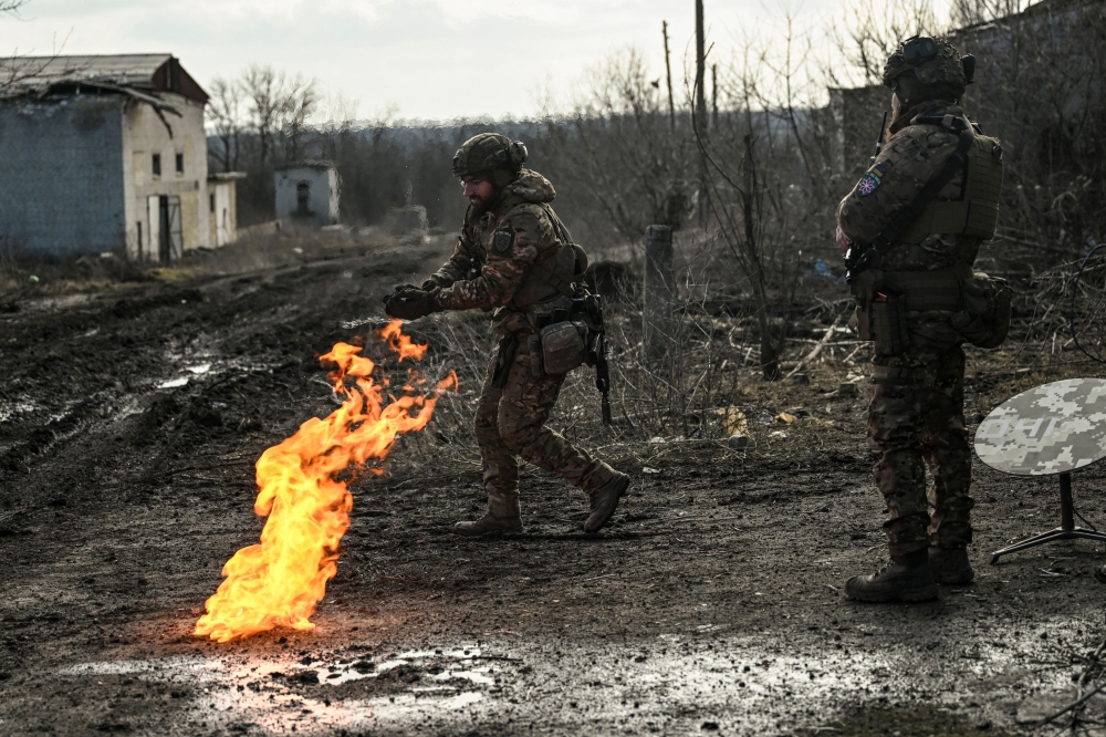 Ukrainian servicemen light a fire with gun powder to get warm near the city of Bakhmut in the region of Donbas on March 5, 2023, amid the Russian invasion of Ukraine. (Photo by Aris Messinis / AFP)