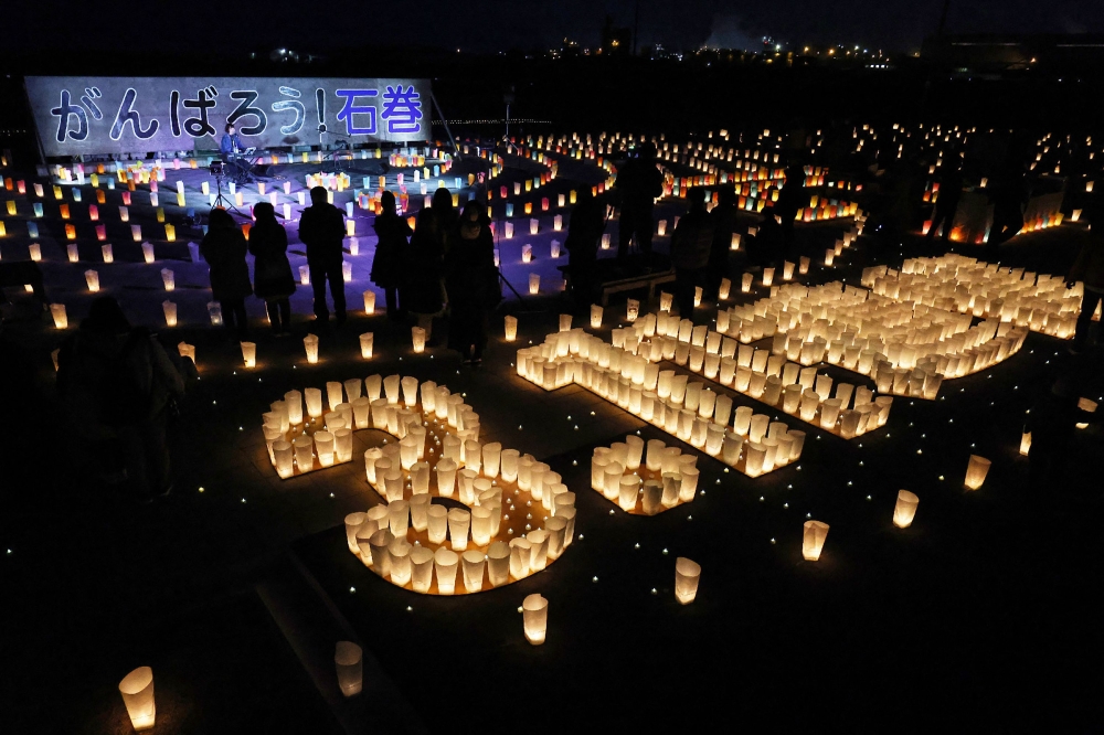 People attend a vigil with lanterns to mark the 12th anniversary of 2011 earthquake, tsunami and nuclear disaster, in Ishinomaki, Miyagi Prefecture on March 11, 2023. (Photo by JIJI PRESS / AFP)