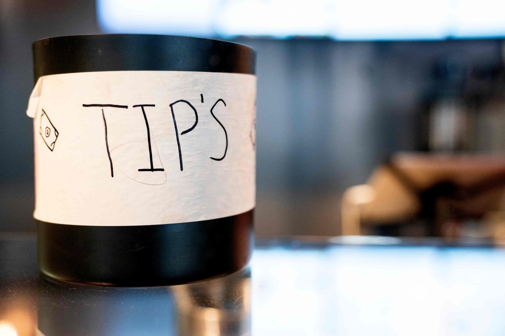 A tip jar sits on a countertop at a store in Washington, DC, on March 17, 2023. (Photo by Stefani Reynolds / AFP)