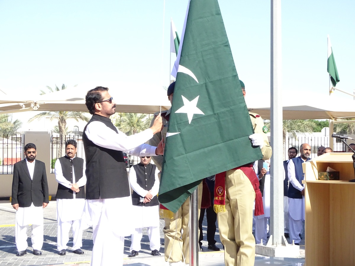 Pakistan Ambassador to Qatar H E Muhemmed Aejaz (right) hoisting the national flag during the ceremony to mark the Pakistan National Day as officials and guests look on.