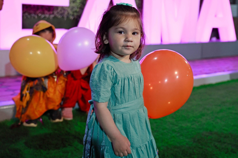 Afghan toddler Maryam, who was bundled onto an evacuation flight after her parents were killed in a huge bomb blast at Kabul airport in 2021, reunites with her uncle and sisters at an orphanage in Doha on March 27, 2023. Photos by KARIM JAAFAR / AFP