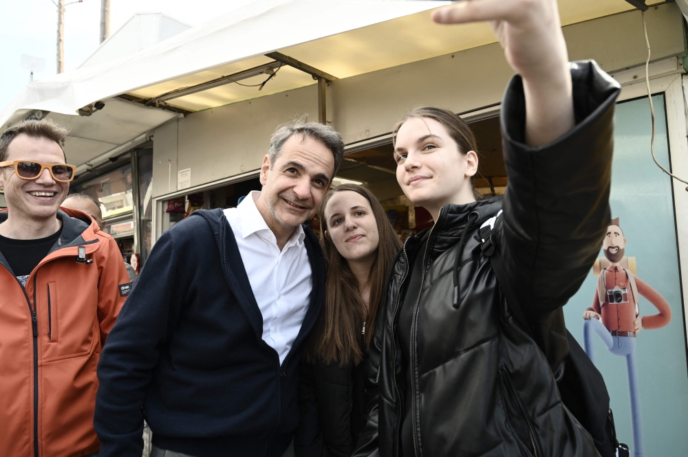 Greece's Prime Minister Kyriakos Mitsotakis takes a selfie photograph during a visit in the region of Evros to campaign and to sign the extension of the border fence project, in Didymoteicho, eastern Greece, on March 31, 2023.(Photo by Sakis Mitrolidis / AFP)