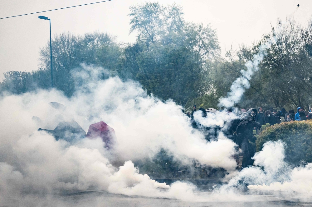 Protesters clash with police officers during a demonstration on the 12th day of action after the government pushed a pensions reform through parliament without a vote, using the article 49.3 of the constitution, in Nantes, western France on April 13, 2023.  (Photo by LOIC VENANCE / AFP)