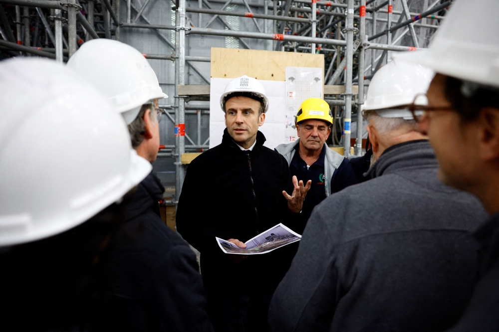 French President Emmanuel Macron, wearing a working helmet, talks with conservation experts as he visits the restoration site at the Notre-Dame de Paris Cathedral, which was damaged in a devastating fire four years ago, in Paris, France, April 14, 2023. (Photo by SARAH MEYSSONNIER / POOL / AFP)