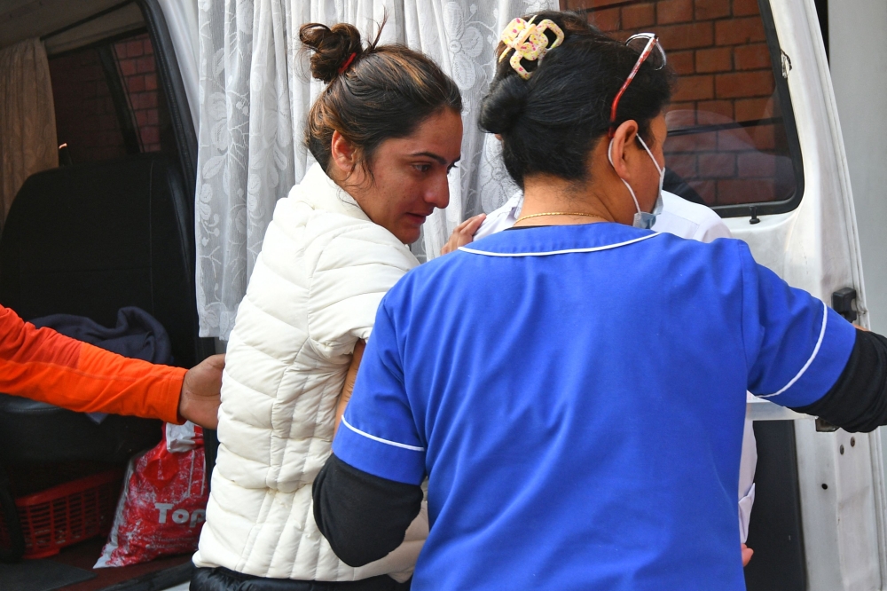 A member of medical staff helps India's record-holding climber Baljeet Kaur after being rescued from the treacherous Annapurna mountain range, at a hospital in Kathmandu on April 18, 2023. (Photo by Prakash Mathema / AFP)