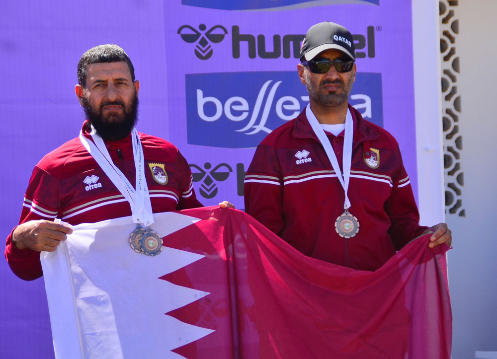 Qatar team members pose with the national flag.  