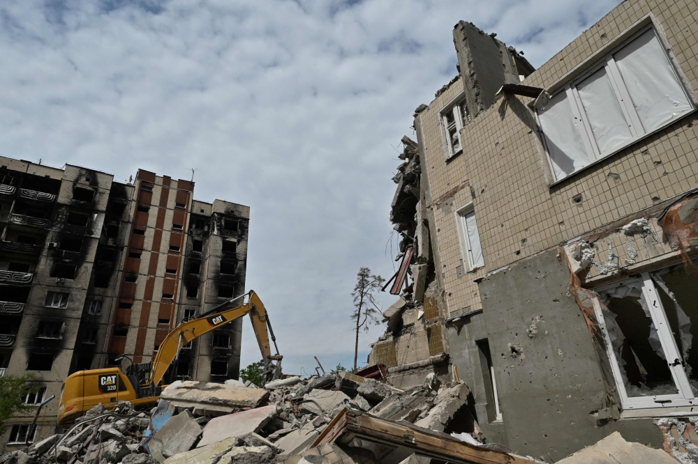 Workers dismantle a heavily damaged residential building in Irpin, on May 4, 2023, amid the Russian invasion of Ukraine. (Photo by Genya Savilov / AFP)