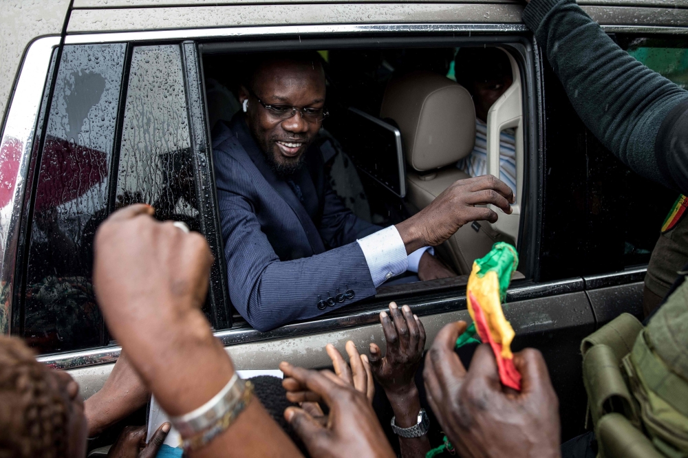 (FILES) Ousmane Sonko (C), President of the opposition party Senegalese Patriots for Work, Ethics and Brotherhood (PASTEF), waves good bye to his supporters at the HLM basic school in Ziguinchor on July 3, 2022. (Photo by MUHAMADOU BITTAYE / AFP)