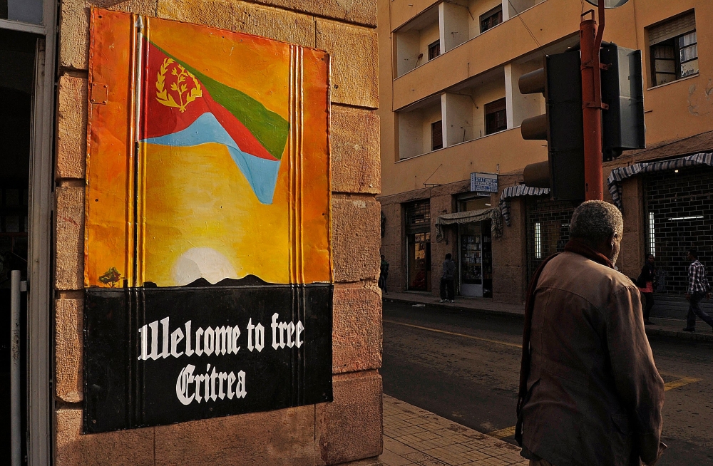 A man waits to cross the road beside a patriotic poster in Asmara, Eritrea, on July 18, 2013. Parties, music and dancing lasted the entire month to commemorate Eritrea's liberation from Ethiopian rule in May 1991, and its overwhelming support for independence in a UN-backed referendum two years later. (Photo by Jenny VAUGHAN / AFP)
