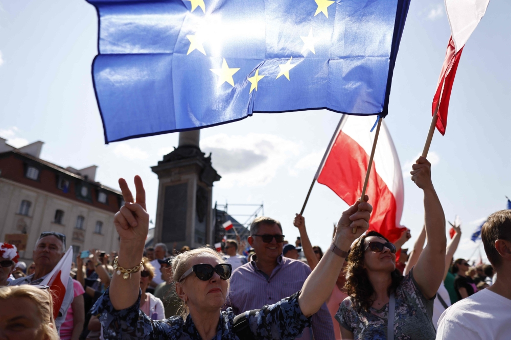 People wave the European and Polish flags during an anti-government demonstration organized by the opposition in Warsaw on June 4, 2023. (Photo by Wojtek Radwanski / AFP)