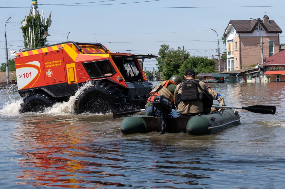 Ukrainian security forces transport local residents in a boat during an evacuation from a flooded area in Kherson on June 7, 2023, following the destruction of Kakhovka hydroelectric power plant dam. Photo by ALEKSEY FILIPPOV / AFP