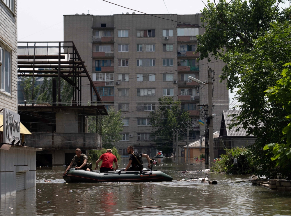 Ukrainian security forces ride in a boat during an evacuation from a flooded area in Kherson on June 7, 2023, following damages sustained at Kakhovka hydroelectric power plant dam. Photo by ALEKSEY FILIPPOV / AFP