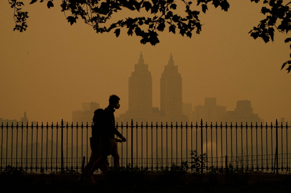 People walk in Central Park as smoke from wildfires in Canada cause hazy conditions in New York City on June 7, 2023. Photo by TIMOTHY A. CLARY / AFP