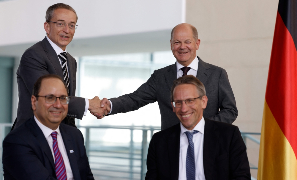 Pat Gelsinger (background left), CEO of US multinational corporation and technology company Intel, and German Chancellor Olaf Scholz (background right) shake hands after State Secretary at the Chancellery Joerg Kukies (foreground right) and Intel Executive Vice President Keyvan Esfarjani signed an agreement between the German government and Intel on June 19, 2023 at the Chancellery in Berlin. (Photo by Odd Andersen / AFP)