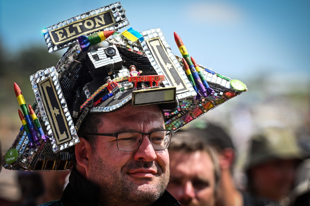 A festival goer wears a Elton John themed hat on day 5 of the Glastonbury festival in the village of Pilton in Somerset, southwest England, on June 25, 2023. (Photo by Oli Scarff / AFP)