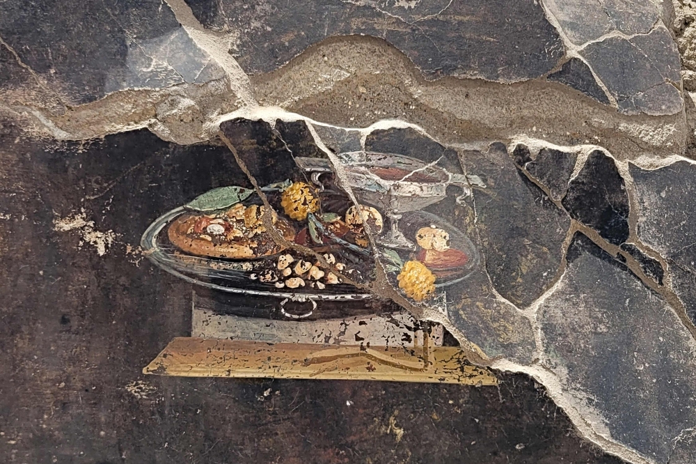 This handout photo taken and released on 25 June by Parco Archeologico di Pompei (Archaeological Park of Pompeii), shows a 2,000-year-old Pompeian painting, a still life, found by the new Regio IX excavations, depicted on the wall of an ancient Pompeian house that could be a distant ancestor of modern pizza. (Photo by Handout / Parco Archeologico di Pompei press office / AFP) 
