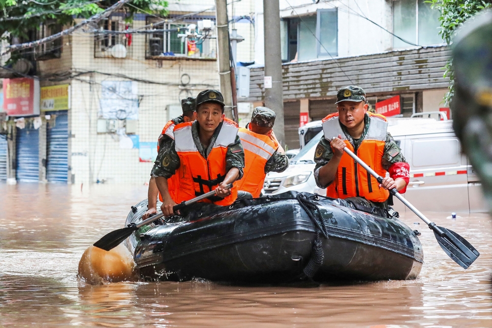 (FILES) This file photo taken on July 4, 2023 shows paramilitary policemen searching an area after it was flooded by heavy rain in China's southwestern Chongqing. (Photo by AFP) / China OUT