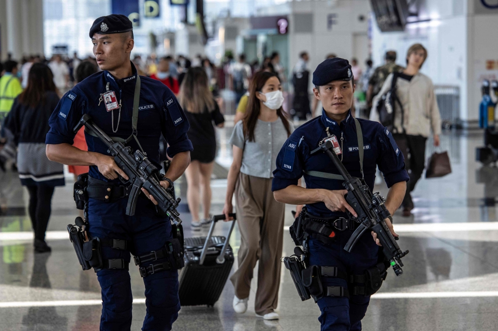 Armed policemen patrol Hong Kong International Airport on July 6, 2023. (Photo by ISAAC LAWRENCE / AFP)