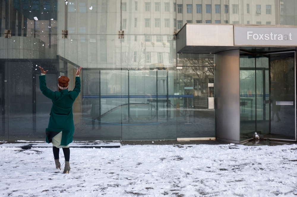 A woman throws snow in the air at a plaza in front of an office building in Johannesburg on July 10, 2023. Photo by Wikus de Wet / AFP